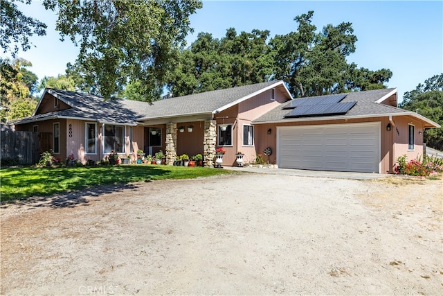 single story home featuring a front yard, a garage, and solar panels