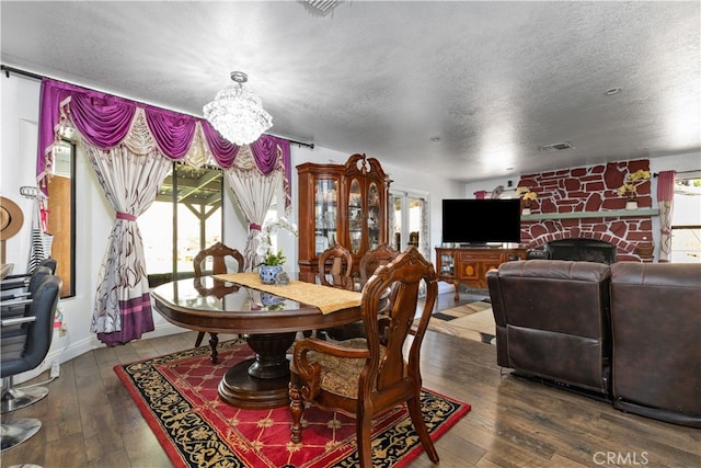 dining room with a textured ceiling, dark wood-type flooring, and plenty of natural light