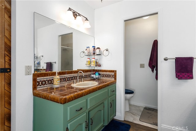 bathroom with tile flooring, vanity with extensive cabinet space, and toilet