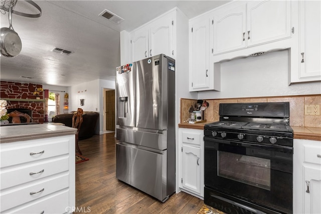 kitchen with black gas range oven, white cabinets, stainless steel fridge with ice dispenser, and dark wood-type flooring