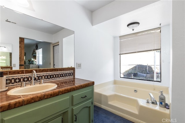 bathroom with backsplash, vanity, and a bath to relax in