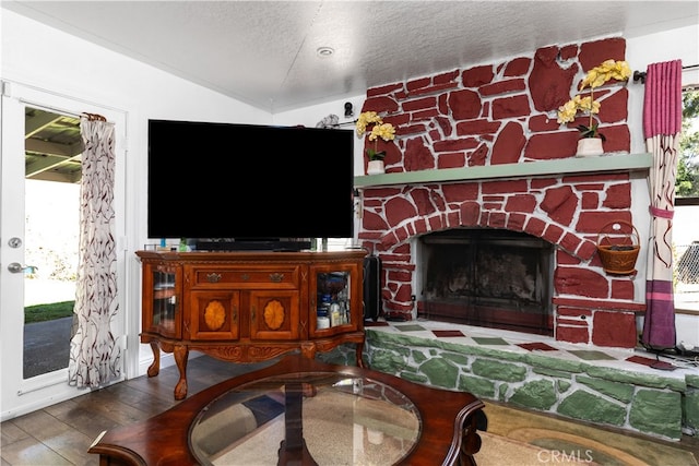 living room featuring vaulted ceiling, a textured ceiling, hardwood / wood-style flooring, and a fireplace