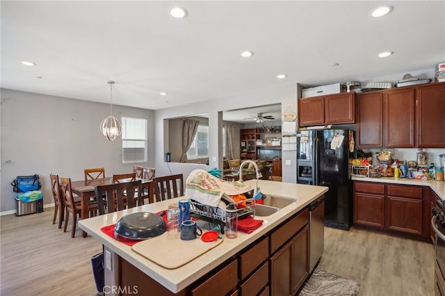 kitchen featuring light hardwood / wood-style floors, a kitchen island with sink, sink, ceiling fan with notable chandelier, and stainless steel appliances