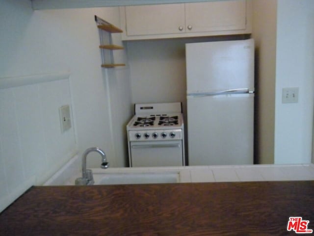 kitchen featuring white cabinets, tile counters, white appliances, and sink