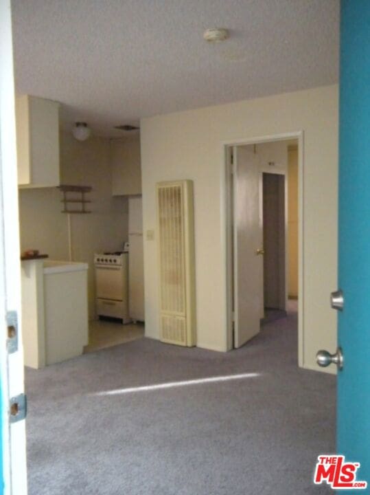 unfurnished bedroom featuring a textured ceiling and light carpet