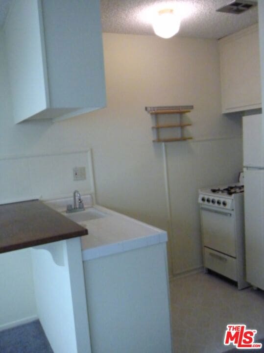 clothes washing area featuring sink and a textured ceiling