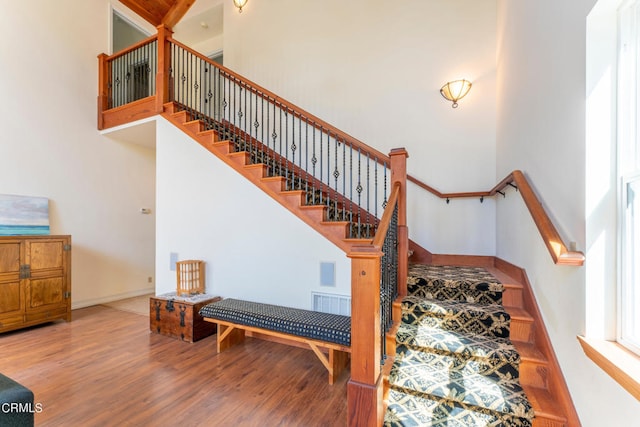 stairs featuring hardwood / wood-style floors and a high ceiling