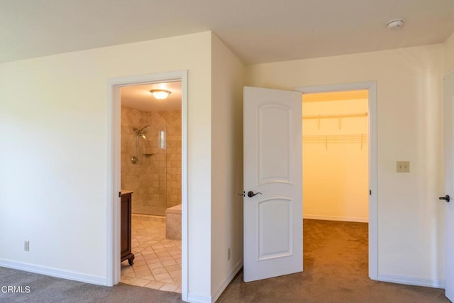 unfurnished bedroom featuring carpet floors, a walk in closet, baseboards, and a closet