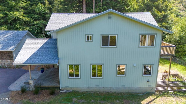 rear view of property with crawl space, fence, and roof with shingles