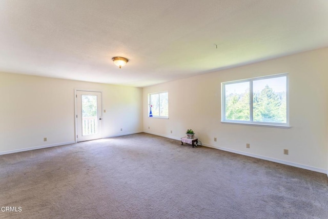 carpeted spare room featuring baseboards