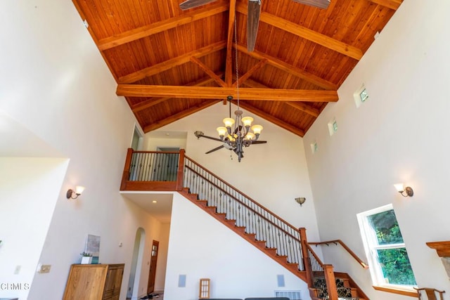staircase featuring high vaulted ceiling, wood ceiling, arched walkways, beam ceiling, and a notable chandelier