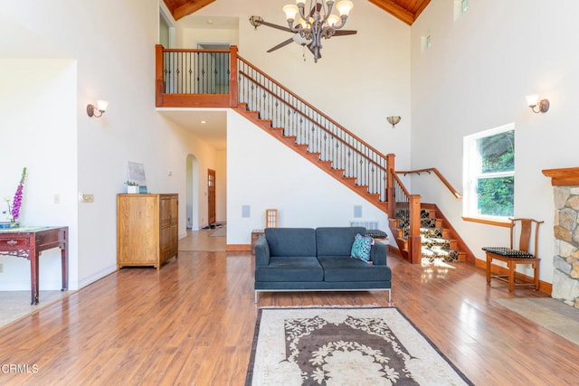 living room with high vaulted ceiling, wood-type flooring, beamed ceiling, and an inviting chandelier