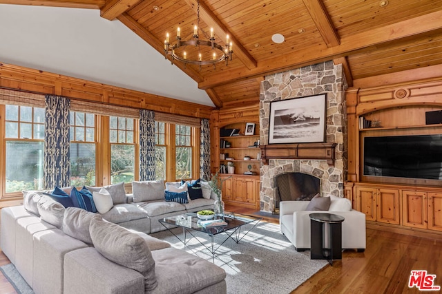 living room featuring an inviting chandelier, a wealth of natural light, hardwood / wood-style floors, and a stone fireplace