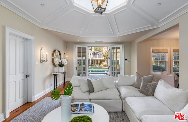 living room with wood-type flooring, ornamental molding, and coffered ceiling