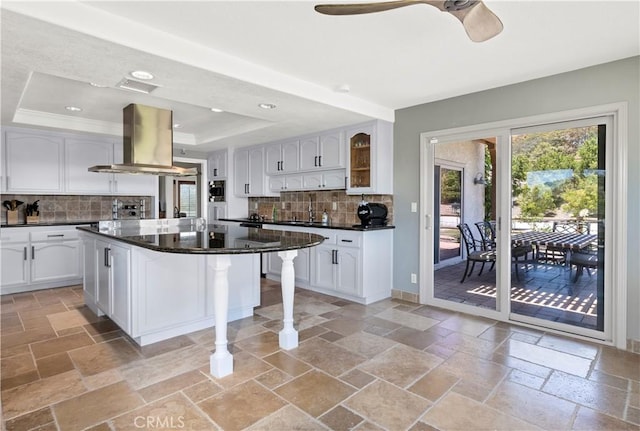 kitchen with dark stone counters, white cabinetry, range hood, and tasteful backsplash