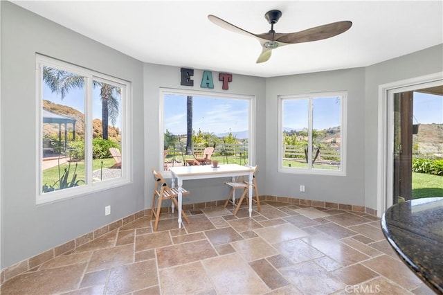 unfurnished sunroom featuring a wealth of natural light and ceiling fan