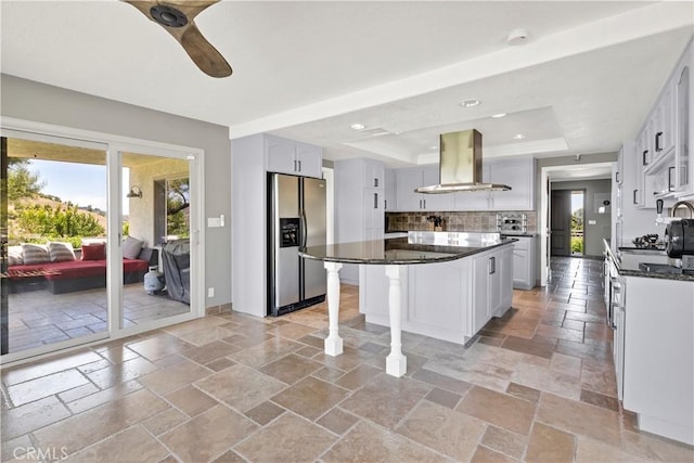 kitchen featuring a wealth of natural light, a center island, range hood, and stainless steel refrigerator with ice dispenser