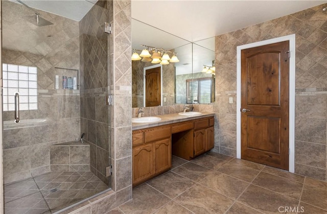 bathroom with a wealth of natural light, vanity, a shower with shower door, and tile walls