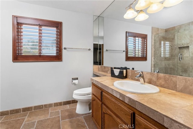 bathroom featuring vanity, a healthy amount of sunlight, toilet, and a shower with door