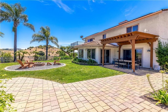 back of house with a yard, a pergola, a patio, and an outdoor fire pit