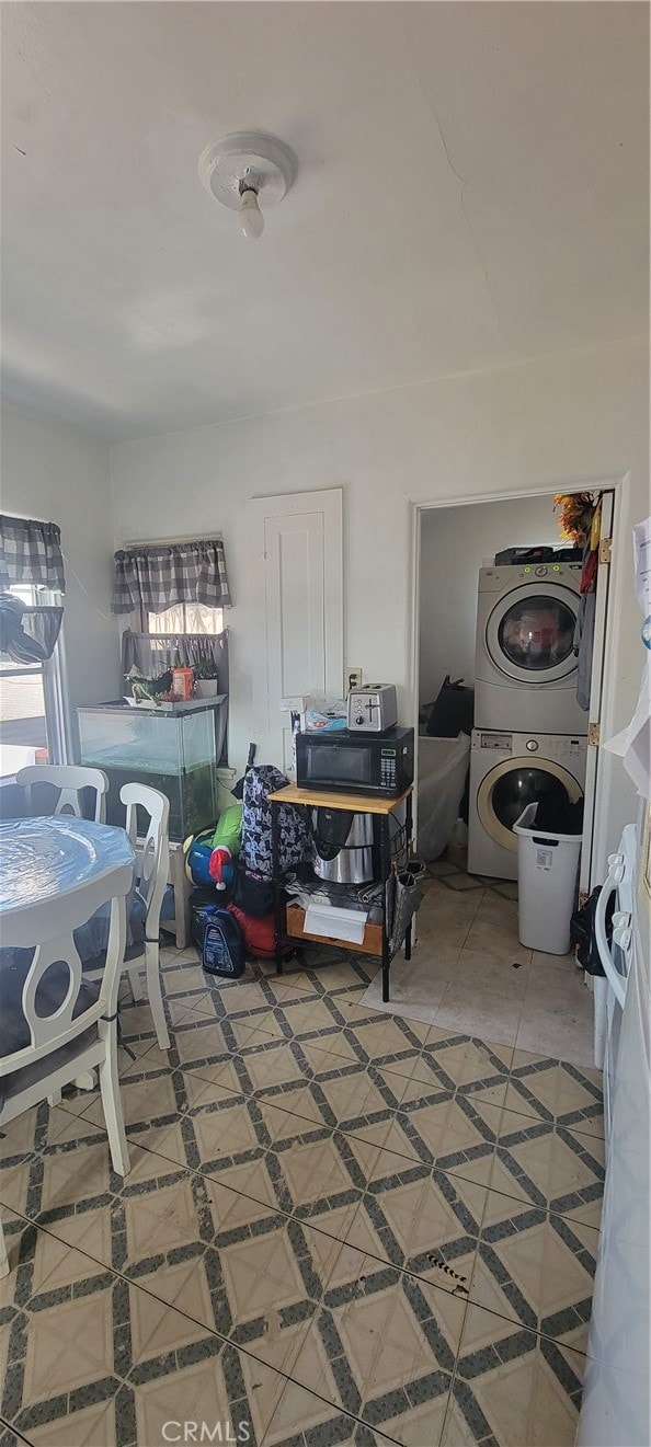 washroom with stacked washing maching and dryer and tile patterned floors