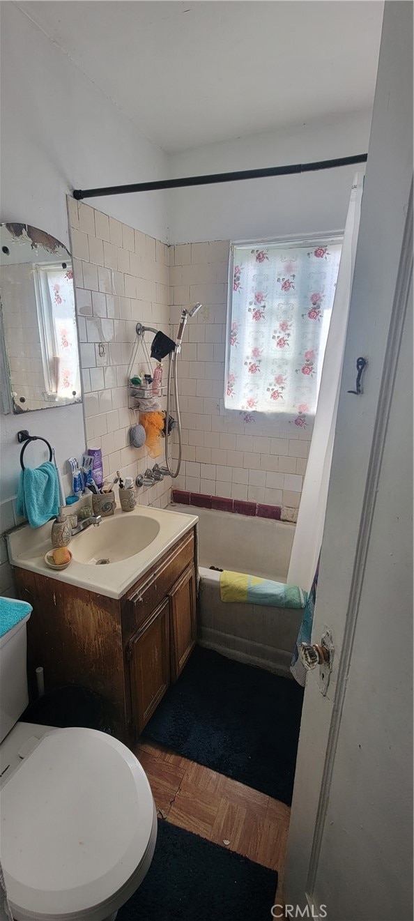 full bathroom featuring shower / bath combo with shower curtain, parquet floors, vanity, and toilet