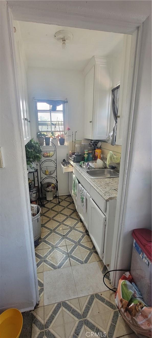 1348 E 21st St, Los Angeles, CA 90011 - kitchen featuring a sink, white cabinetry, light countertops, and light tile patterned flooring