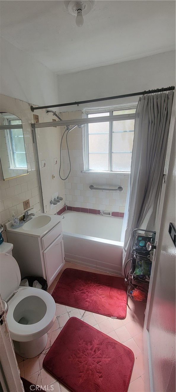 full bathroom featuring a healthy amount of sunlight, shower / bath combo, toilet, and tile patterned floors