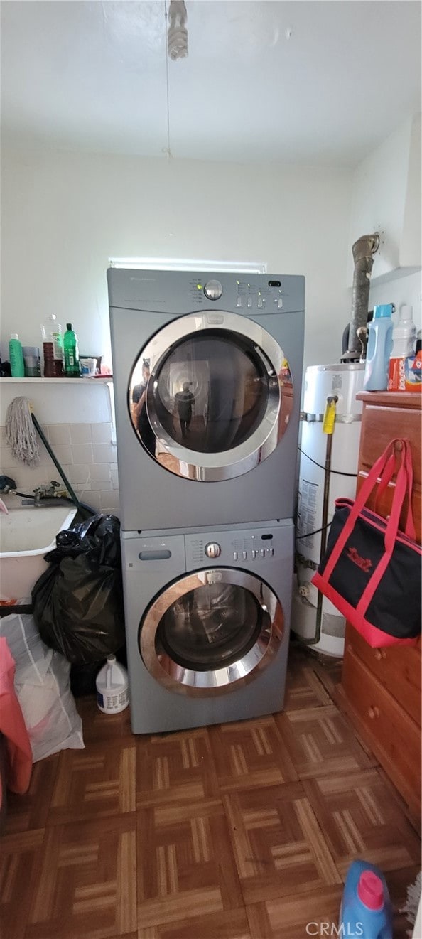 laundry room featuring gas water heater, stacked washer and dryer, and dark parquet floors