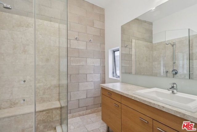 bathroom featuring a tile shower, tile patterned flooring, and vanity