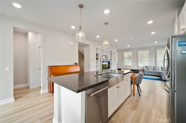 kitchen with a kitchen island with sink, white cabinets, stainless steel appliances, and light wood-type flooring