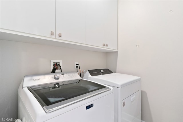 clothes washing area with cabinets and washing machine and dryer