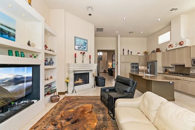 living area featuring built in shelves, visible vents, light tile patterned floors, and a lit fireplace