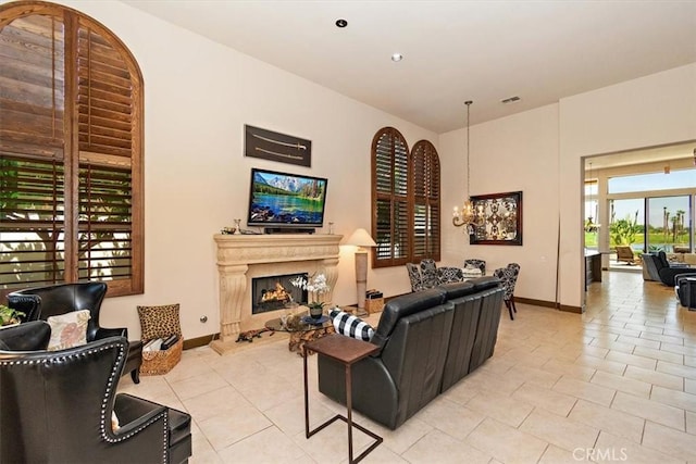 living room with light tile patterned floors, visible vents, baseboards, a fireplace, and a chandelier