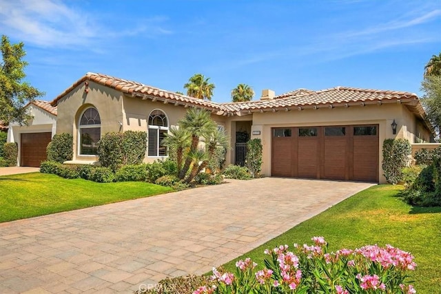 mediterranean / spanish-style home featuring a garage, a front lawn, and stucco siding