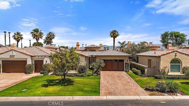 mediterranean / spanish home featuring stucco siding, an attached garage, decorative driveway, and a front yard