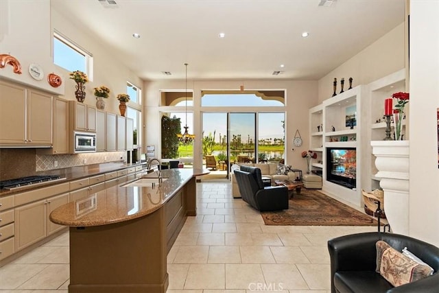 kitchen with gas cooktop, light stone counters, a sink, stainless steel microwave, and open floor plan