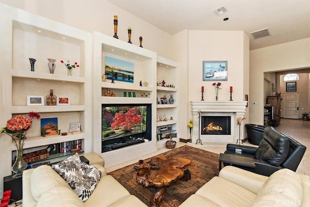 living room featuring visible vents, built in shelves, and a fireplace with flush hearth