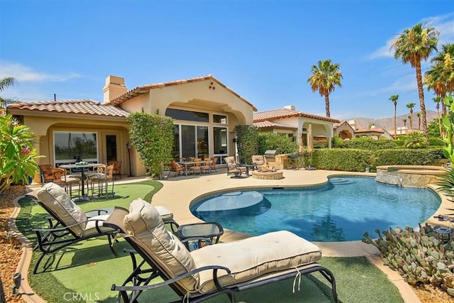 back of house with stucco siding, a pool with connected hot tub, a tile roof, a patio, and a chimney