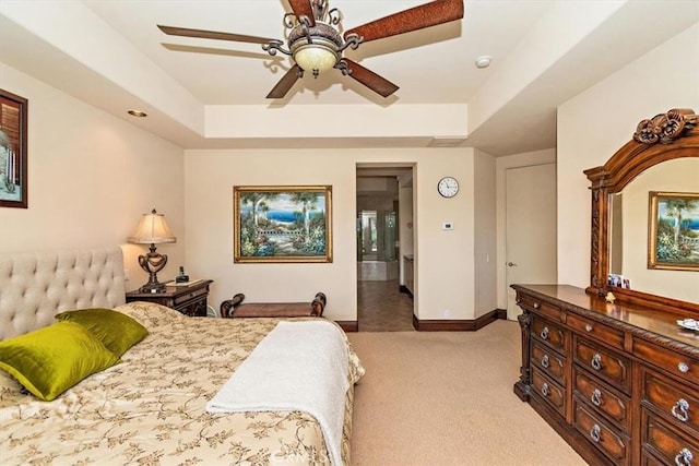 carpeted bedroom with ceiling fan and a raised ceiling