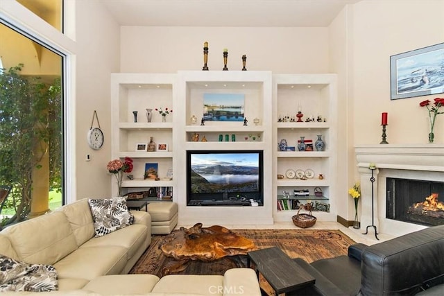 living room featuring built in shelves and a lit fireplace