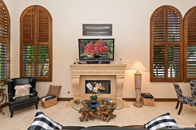 sitting room with tile patterned flooring, baseboards, and a warm lit fireplace