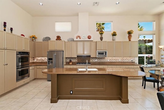 kitchen with visible vents, a high ceiling, a sink, appliances with stainless steel finishes, and cream cabinets