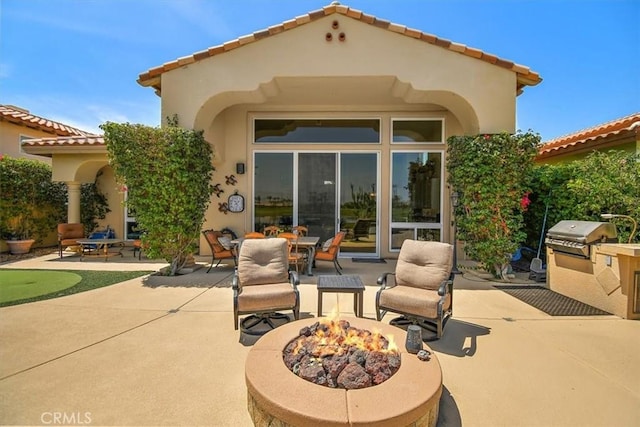 rear view of house with a patio area, stucco siding, and a fire pit