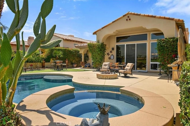 rear view of property featuring a patio area, stucco siding, a pool with connected hot tub, and a fire pit