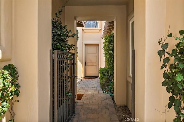 doorway to property featuring stucco siding and a gate