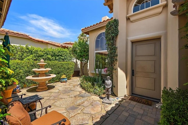 entrance to property with stucco siding and a patio