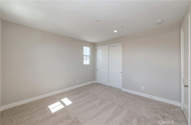 unfurnished bedroom featuring light carpet and a closet