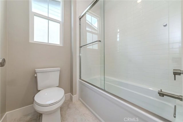 bathroom featuring tile patterned floors, toilet, and shower / bath combination with glass door