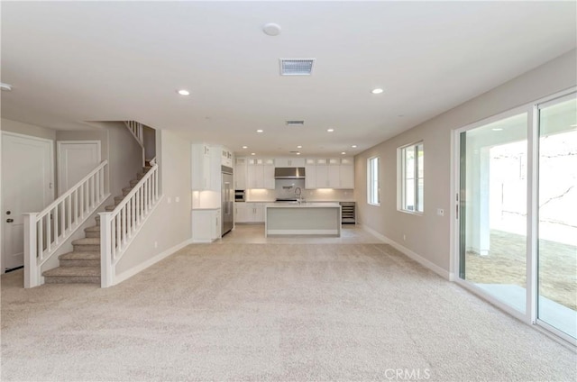 unfurnished living room featuring light colored carpet and sink